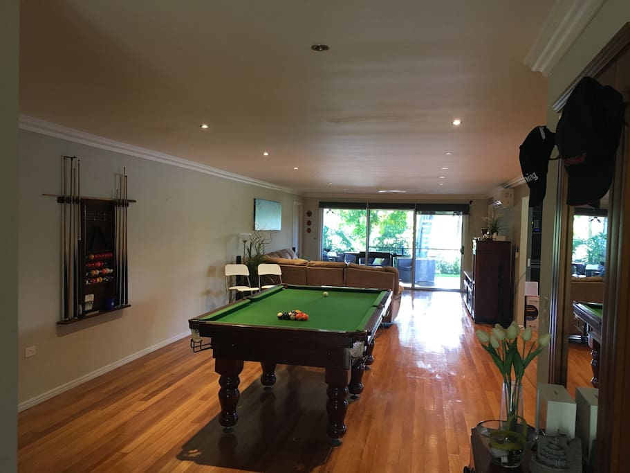 View from the main entrance - pool table, lounge area and full length doors out to back deck, leafy backyard and serene lake views.