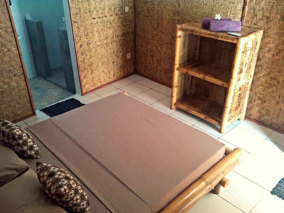 Studio room in Gili Trawangan: Mama J's Cinammon Studio / BEDROOM with BATHROOM AREA: furnished with bamboo bed, open cupboard and bedside table.