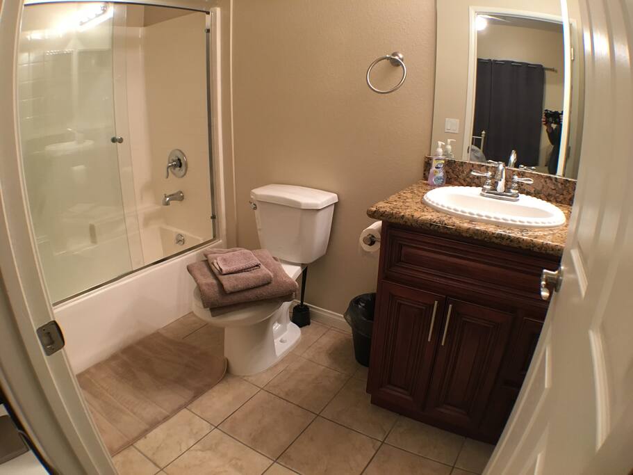 Spacious bathroom with bathtub and towels provided.