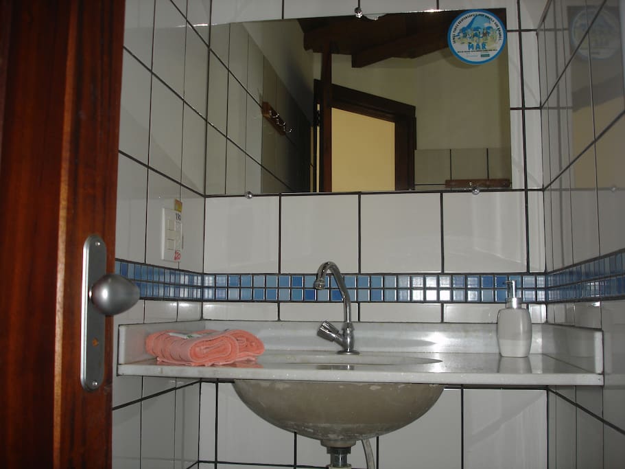 Banheiro confortável, com ducha, espelho, sanitário e pia.