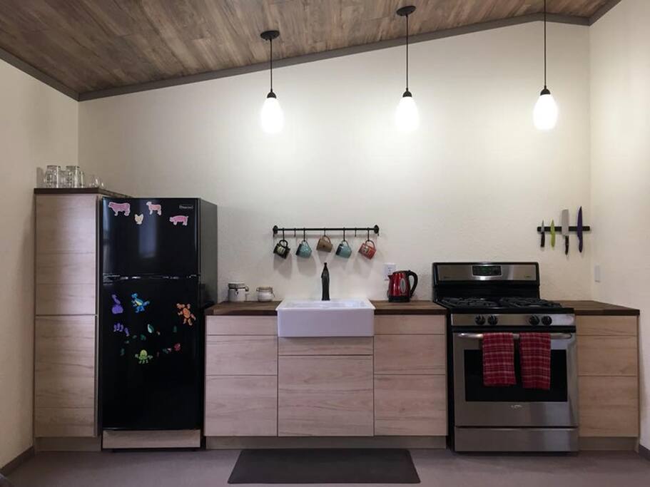 Kitchenette with refrigerator, farmhouse sink, and gas range. Dishes, pots and pans, and utensils provided. Tea kettle, press pot, coffee and tea provided.