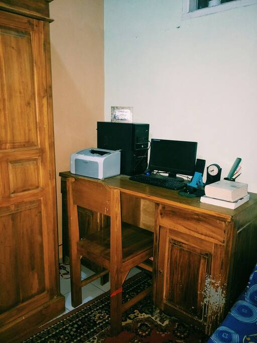 meja belajar beserta komputer, printer, dan berbagai buku siap dibaca