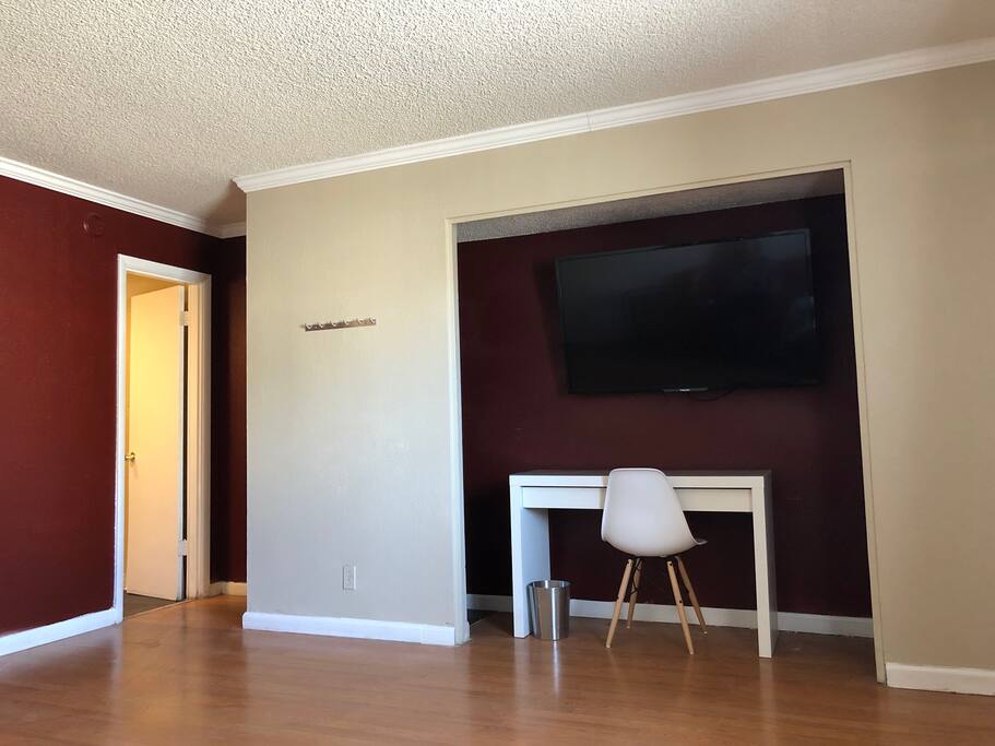 Living room area with 55’ Smart TV, coat rack, work desk.