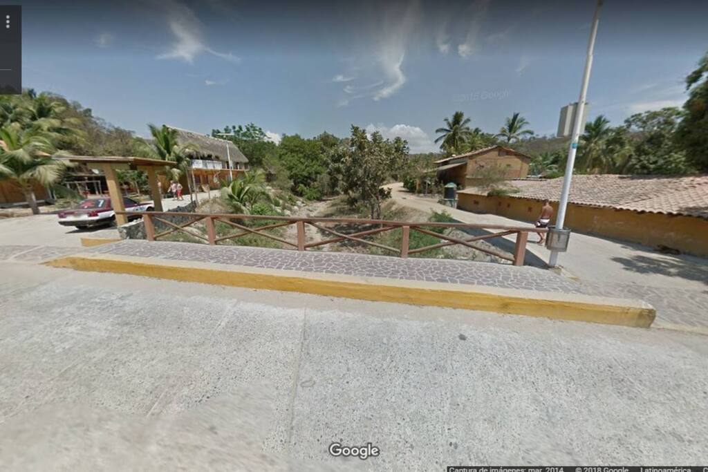 Casa Aldairis se encuentra ubicada a 100mts. de la calle principal, a la altura del puente de la localidad (imagen). Para llegar, se puede subir por calle Aguaje (del lado del taxi) o por calle Parota (la contraria al taxi), y en la unión de estas dos, se encuentra Casa Aldairis, de lado derecho, esquina con calle Guarumbo.