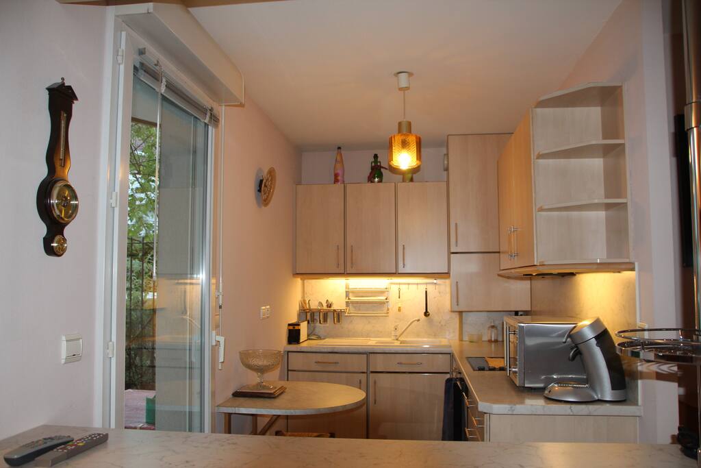 La kitchenette donnant sur une petite terrasse et séparée de la pièce à vivre par le bar.