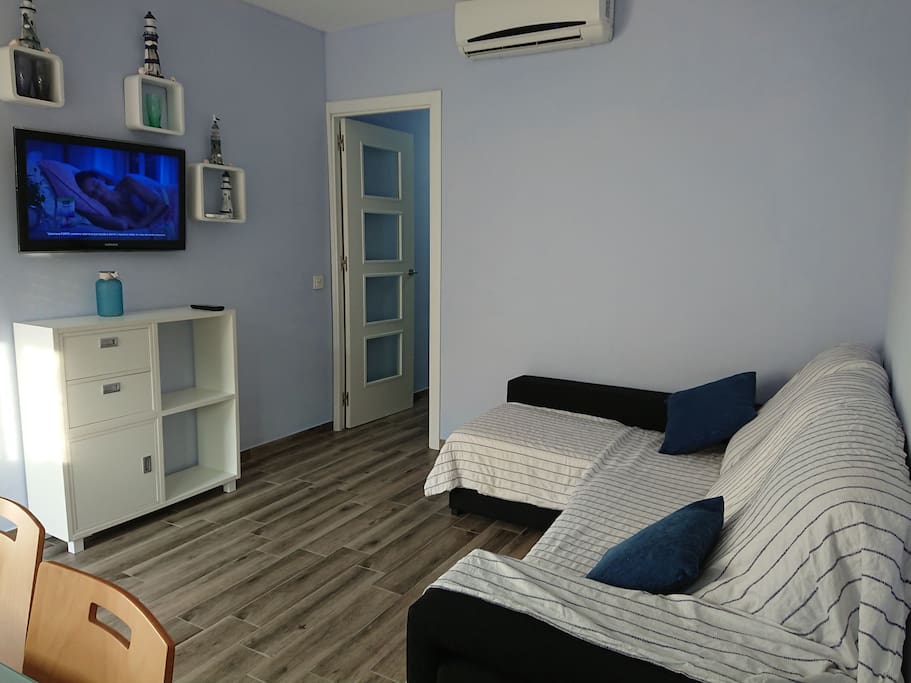Salón con aire acondicionado, tv y sofá chaislong