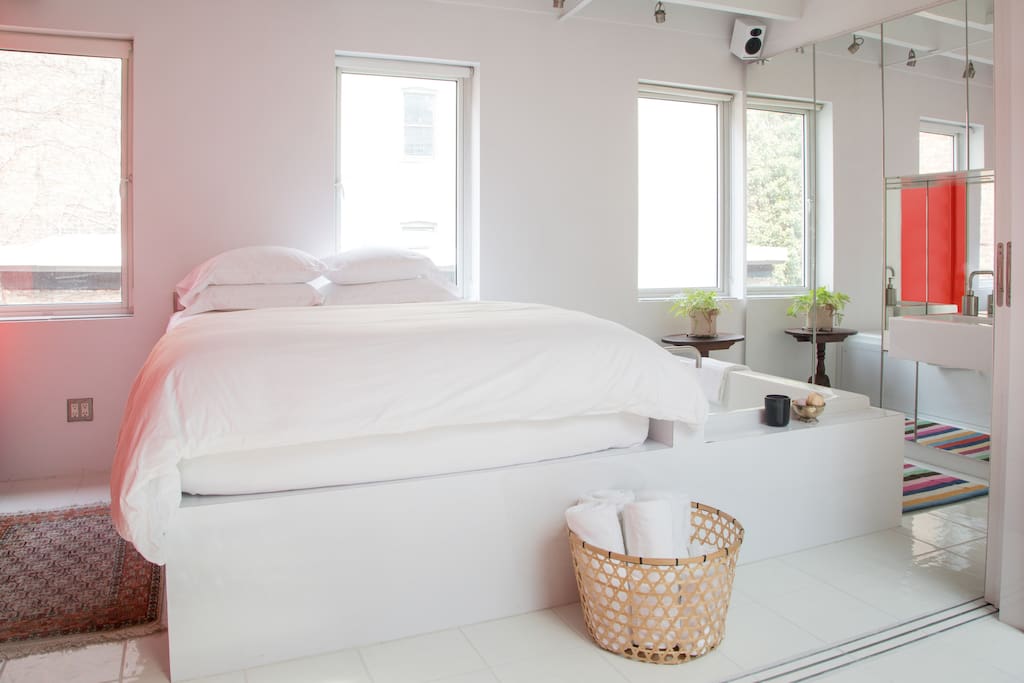 Queen size bed with down pillows, bedding, and high threadcount cotton linens.