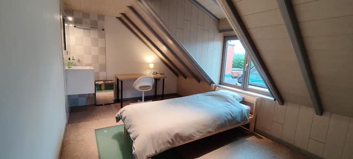 Slaapkamer (eerste verdiep) met eenpersoonsbed, bureau en lavabo