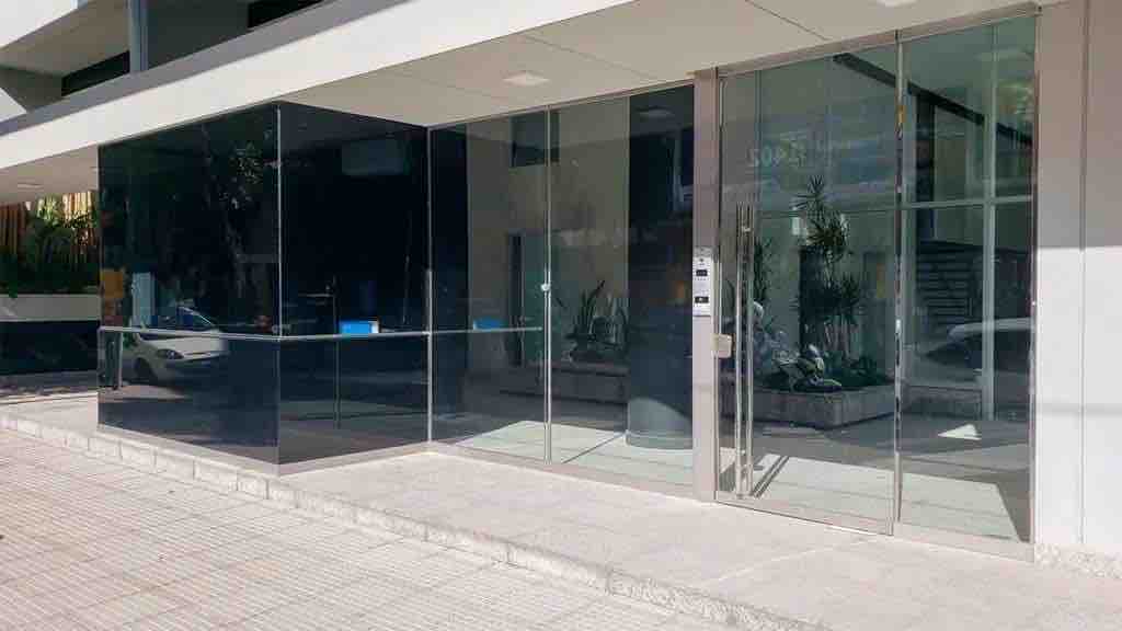 A modern entrance features large glass panels, creating a bright and welcoming first impression. The pathway is lined with minimalistic landscaping elements. An accessible entrance is ensured, providing ease of entry into the building.