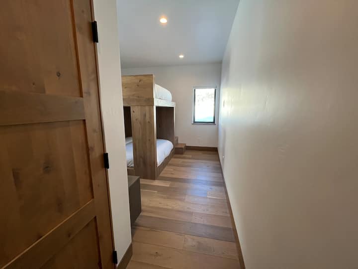 The downstairs bedroom on the east side has custom queen bunkbeds and an en suite bathroom with a tub and shower. There are blackout shades on the windows in the room and a light filtering privacy shade in the bathroom. 