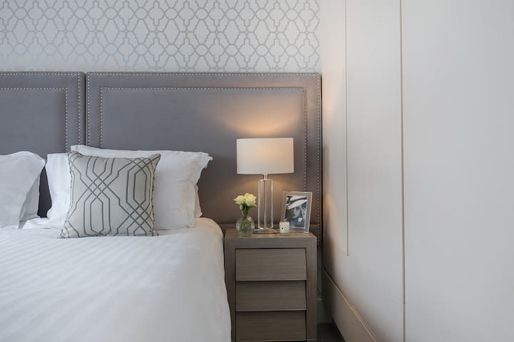 Dormitorio cómodo con sábanas de lujo y una tabla de planchar.