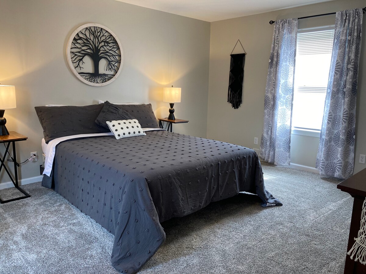 Boven grote slaapkamer met een queensize bed en dressoir. 