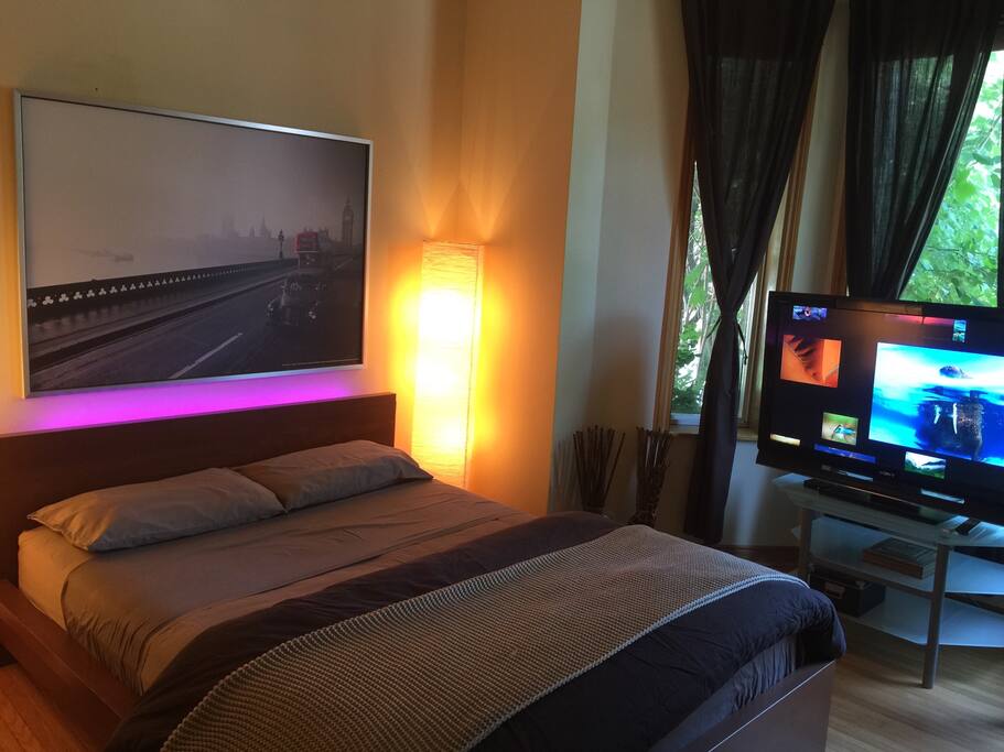 A view of the bedroom area in suite 1. A large comfy bed, TV with Netflix, leather couches.