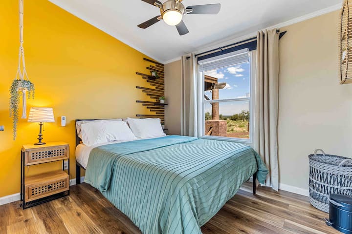 2e chambre avec lit queen size, plantes suspendues et beau mur de contraste.