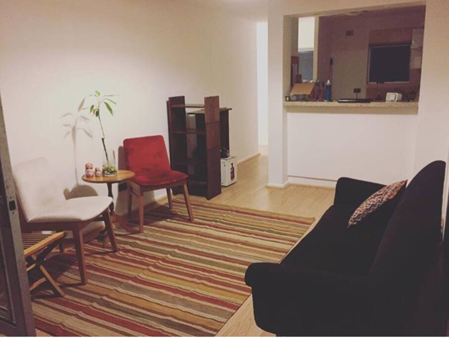 Al fondo se ve la cocina americana, equipada. El sillón para descansar o leer está a la vista.
