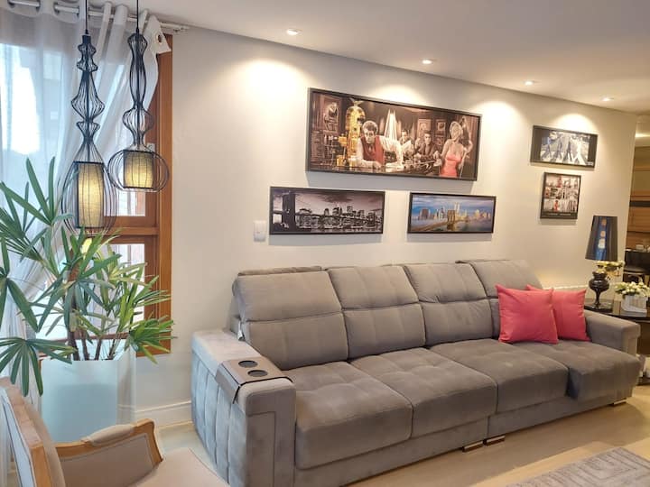 Sala de estar aconchegante com ar-condicionado, Wi-Fi, smart TV e mesa de jantar. Espaço ideal para relaxar no centro de Gramado, perto dos melhores pontos turísticos.