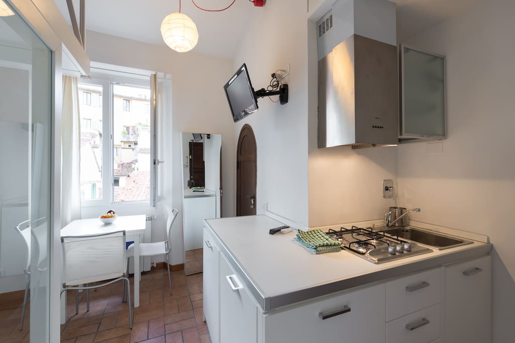 Angolo cucina attrezzato con forno, frigorifero e lavatrice.