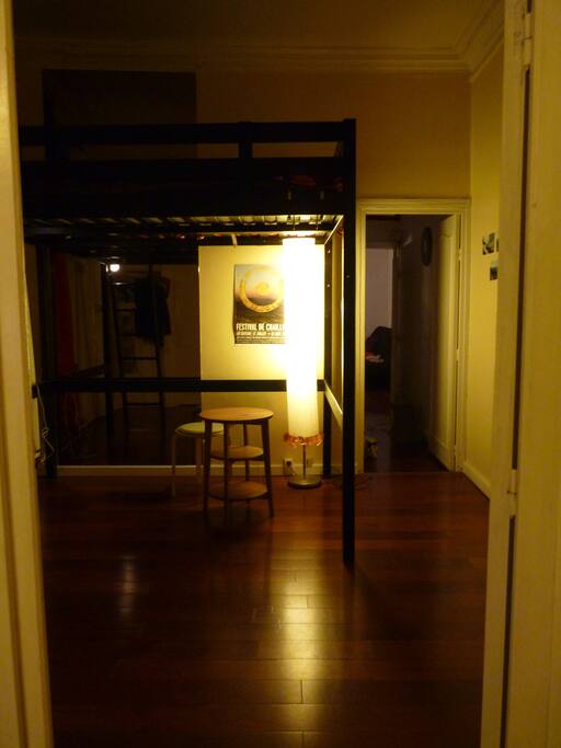 Vue de la chambre (et sur le fond, le salon) à partir de la cuisine. Il y a des portes entre les pièces.
