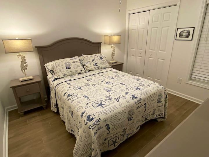 Schlafzimmer mit Queensize-Bett, Kommode mit Waschtischspiegel. Das Badezimmer befindet sich direkt gegenüber dem Flur.