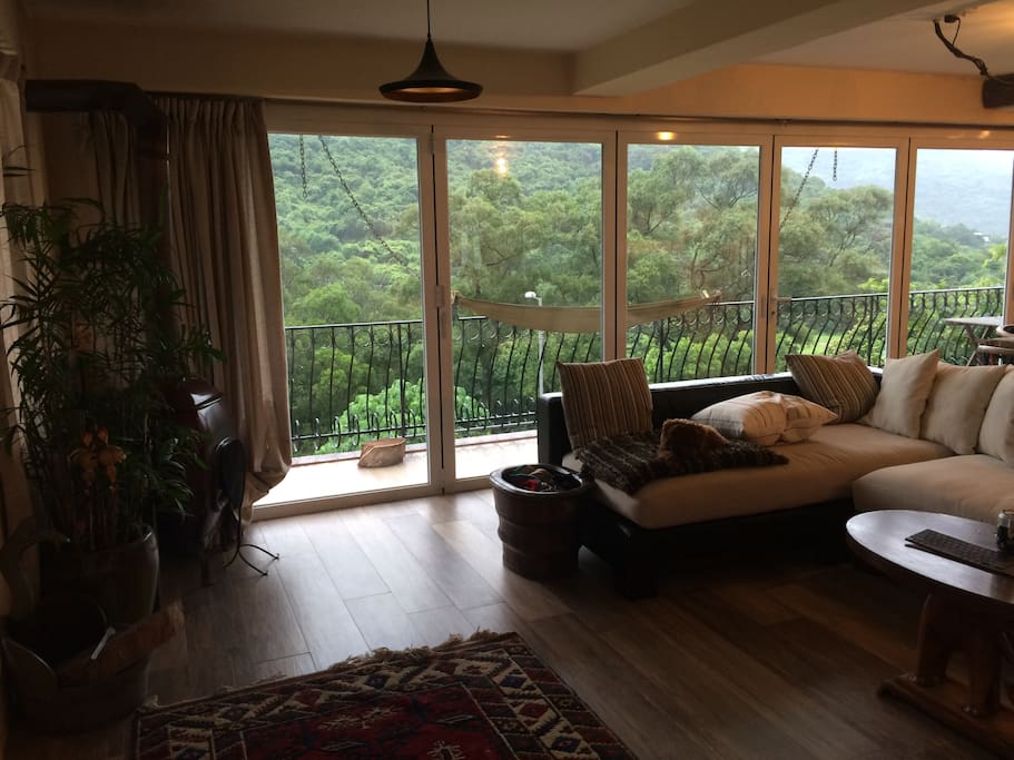 The living room and kitchen windows open completely for a beautiful green view