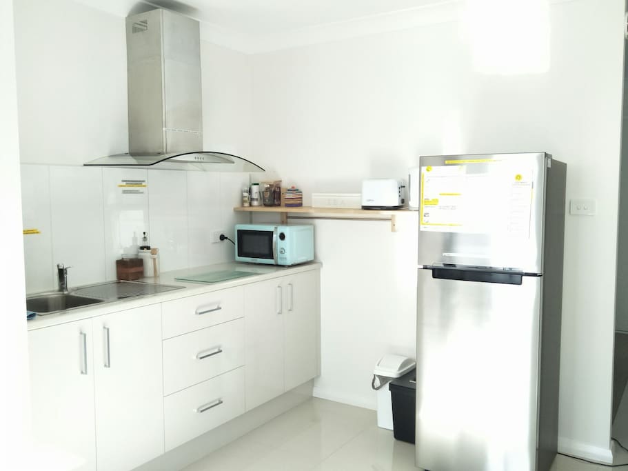 Kitchenette with fridge, microwave, light cooktop, toaster, kettle & utensils.