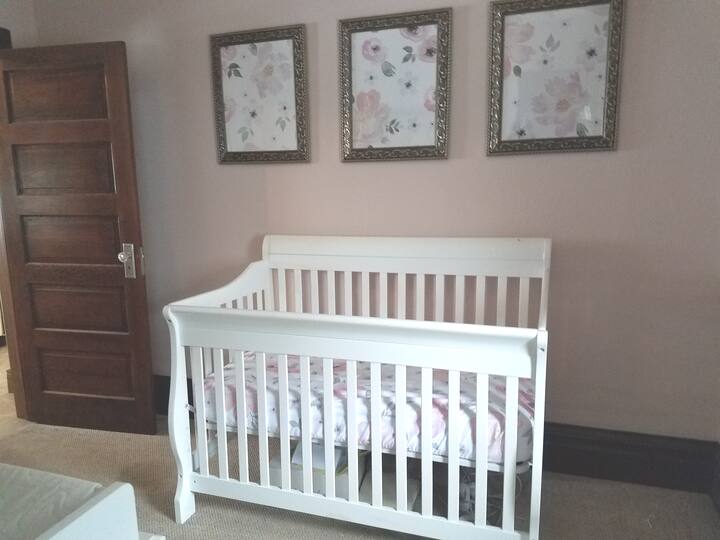 Child's room with convertible crib. Changing table, black out curtains, and rocking chair are also in this room.