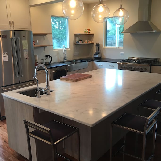 Eight-foot Carrera marble island with prep sink, seating for four, and built-in custom cabinetry.