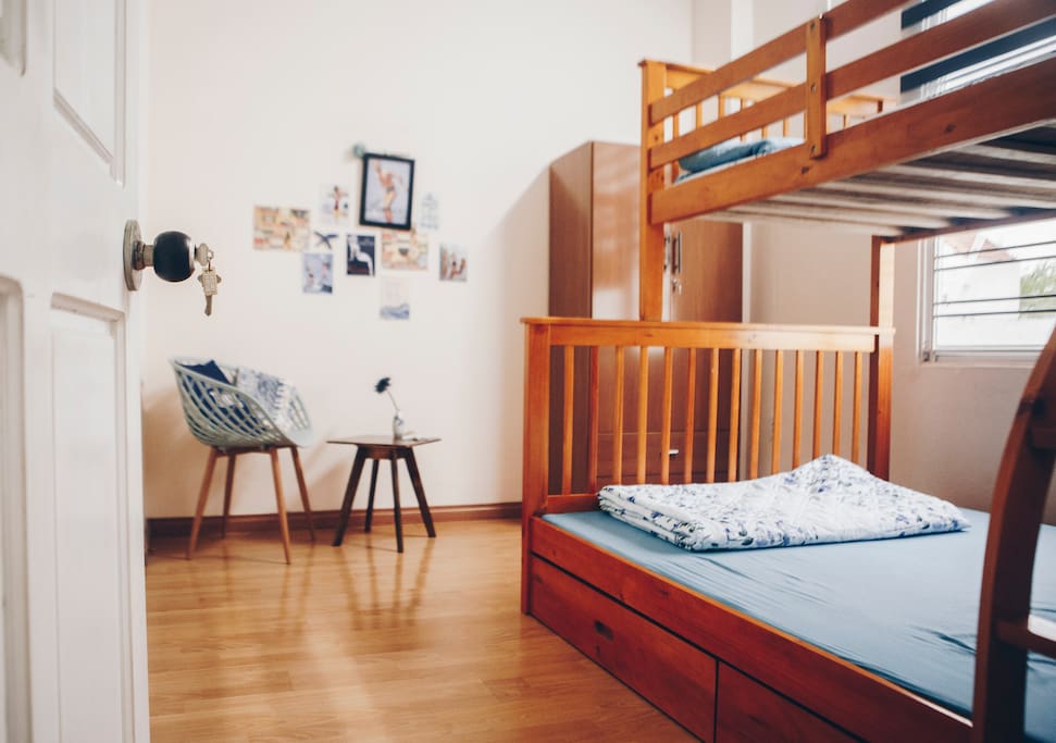 The room is equipped with a bed for three, a wardrobe, a chair and a coffee table
