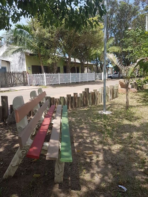 Área verde com bancos em frente à casa.