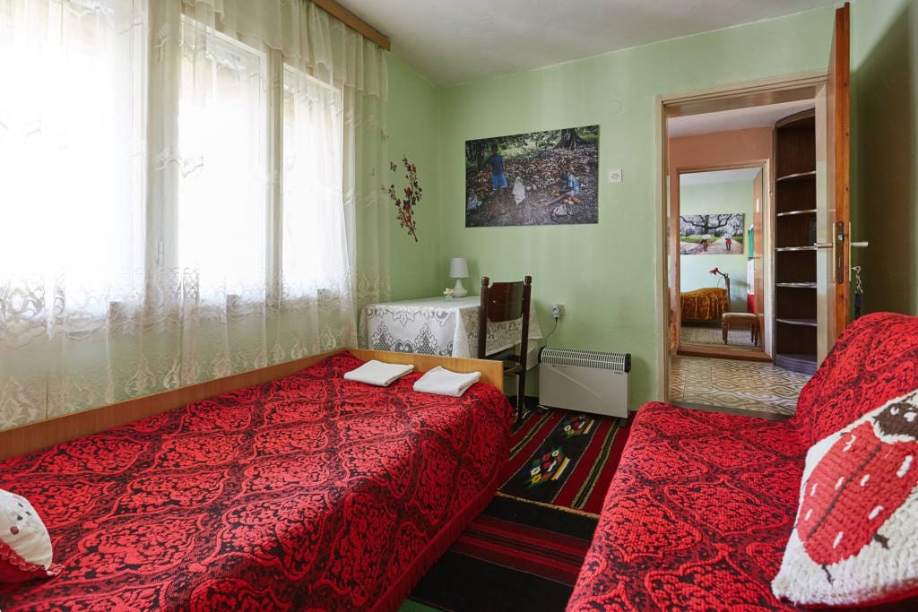 Garden view bedroom with traditional red covers and colorful handwover wool rugs