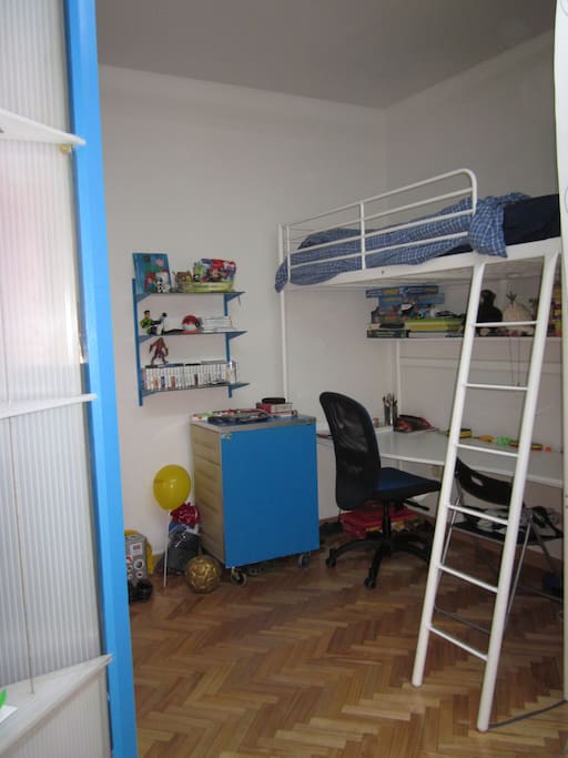 Habitación individual con cama en alto y mesa de despacho