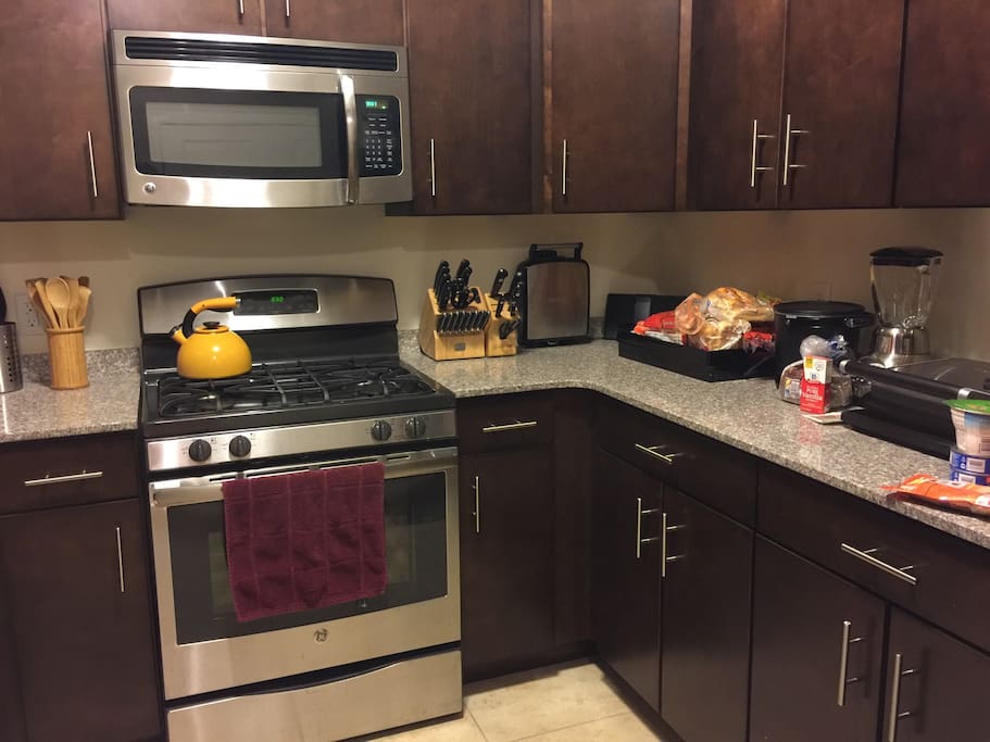 Full kitchen with a toaster, waffle iron, blender, mixer, cutting board, knives, deep fryer, tea kettle, pots and pans, utensils, microwave, refrigerator freezer and dishwasher.