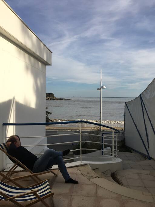 Terrasse en retrait abritée, et couverte par un store, vue sur la plage.