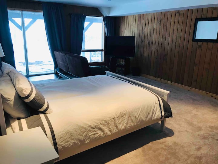 غرفة نوم بسرير بحجم كوين في الطابق السفلي مع تلفزيون بشاشة مسطحة ومشي فوتون 