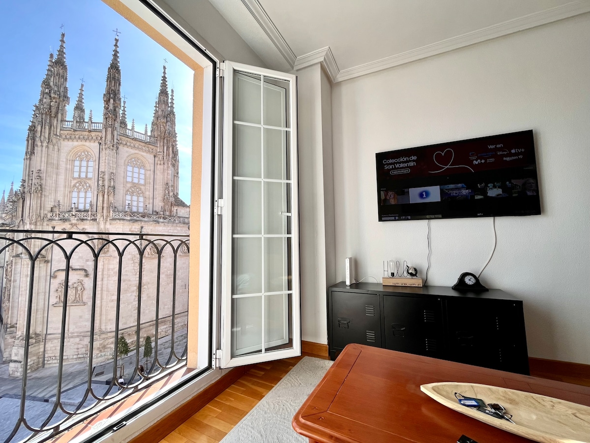 Large windows open to showcase stunning views of the cathedral. A sleek TV is mounted on the wall, and a coffee table sits invitingly in the center of the room, providing a comfortable space to relax and enjoy the surroundings.