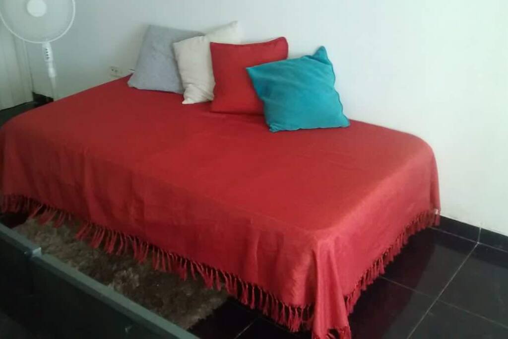 Cama parte del mobiliario del living, frente a amplio ventanal con vista al mar