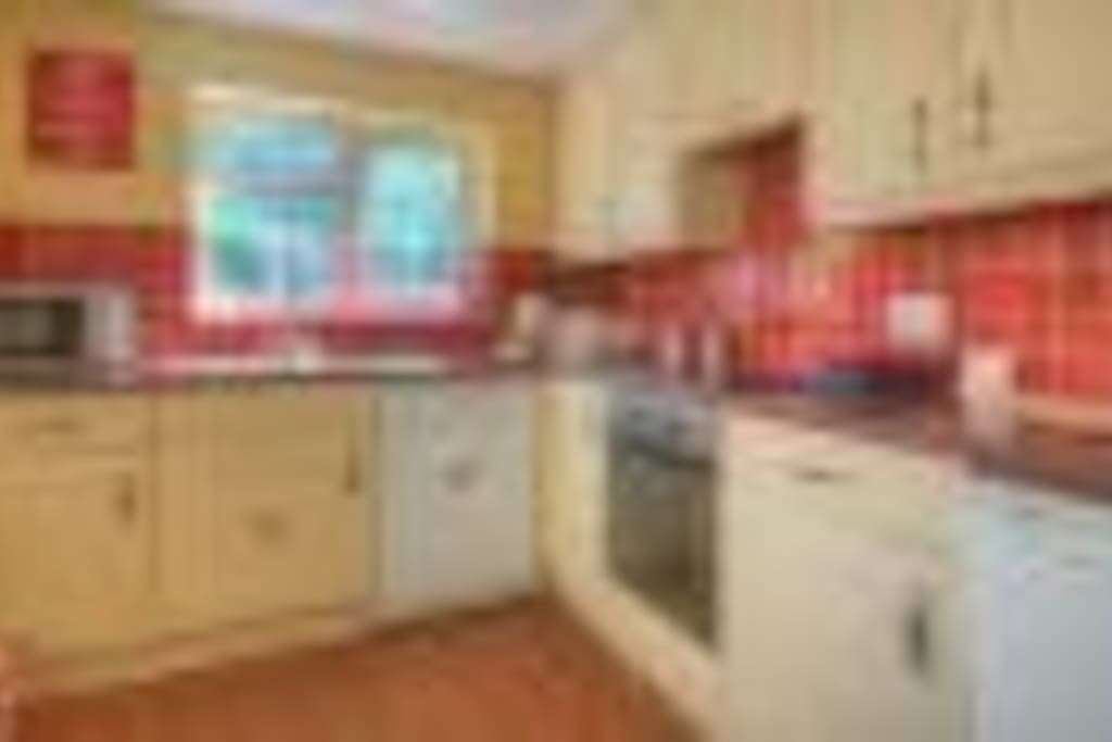 Modern kitchen with oven, hob, microwave, fridge freezer & dishwasher.