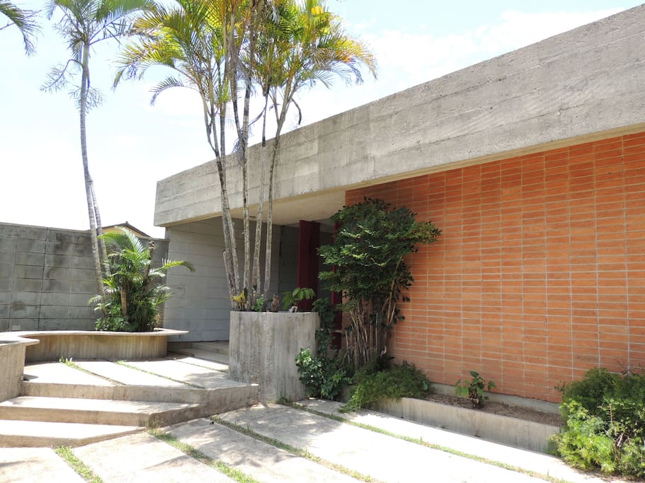 Vista frontal, parte da garagem, jardim e varanda da entrada principal.