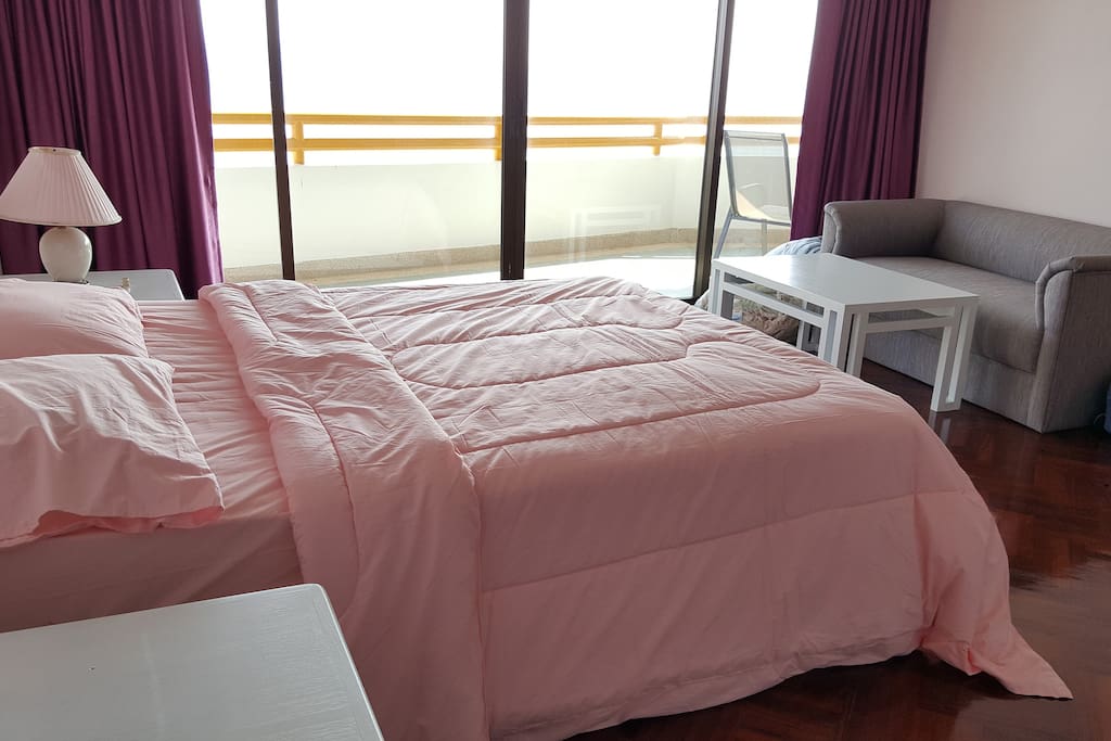 MASTER BEDROOM IS WITH SMALL COUCH AND TABLE AT THE CORNER.