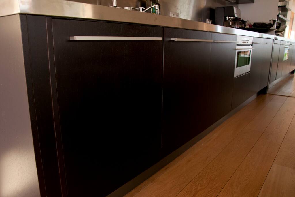 The kitchen has a washing machine, an oven/microwave and a fridge