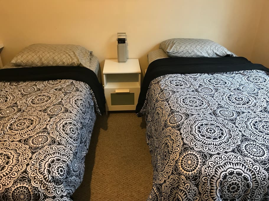Two beds with a nightstand and desk made by IKEA.