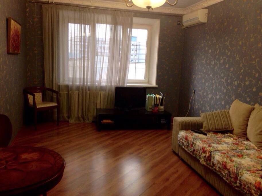 This a living-room. There is a TV-set, a sofa which can be extended to a bed, a cofee table, a couple of chais and an air-conditioner.