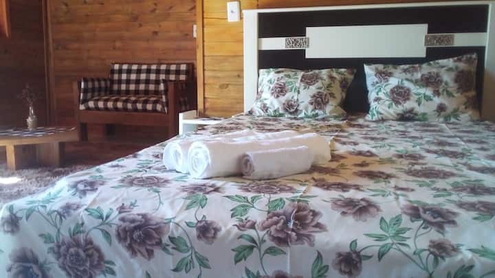 El interior del alojamiento muestra cama doble, sillón y mesa de centro.