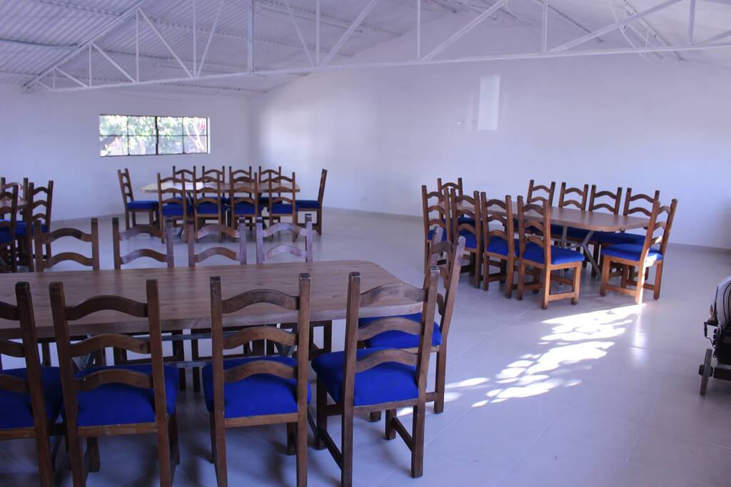 Salón de usos múltiples con 4 mesas grandes y 10 sillas