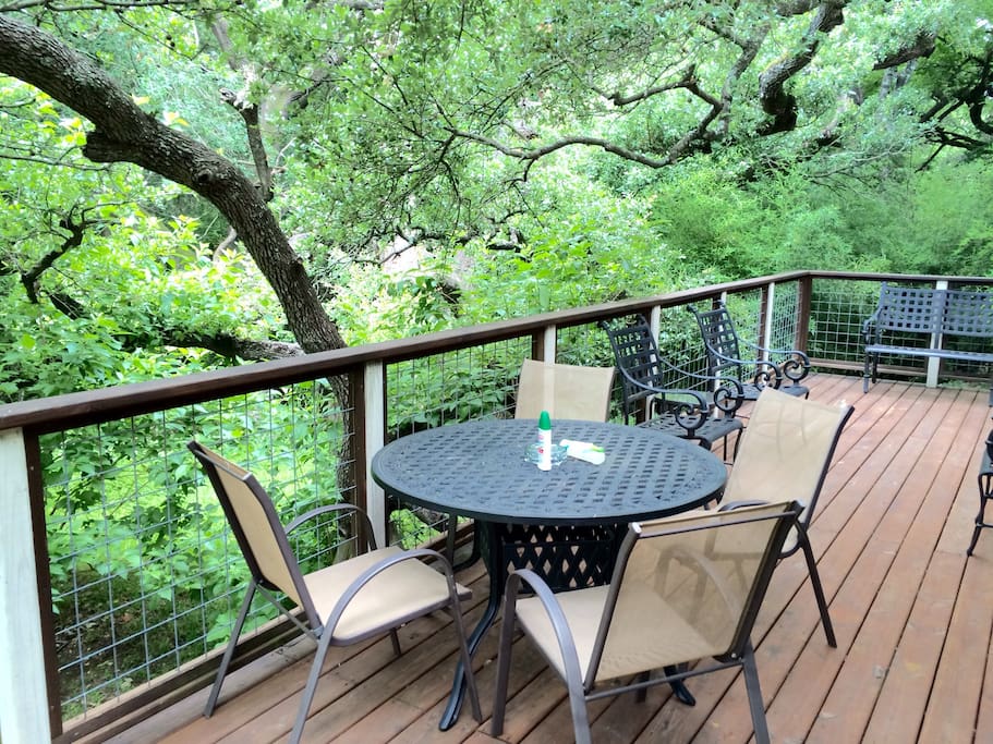 The canopied tree covers back porch that is connected to the den/kitchen /dining common area . Enjoy this peaceful environment while the kids play in the huge lush lawn amongst the trees and flowers .