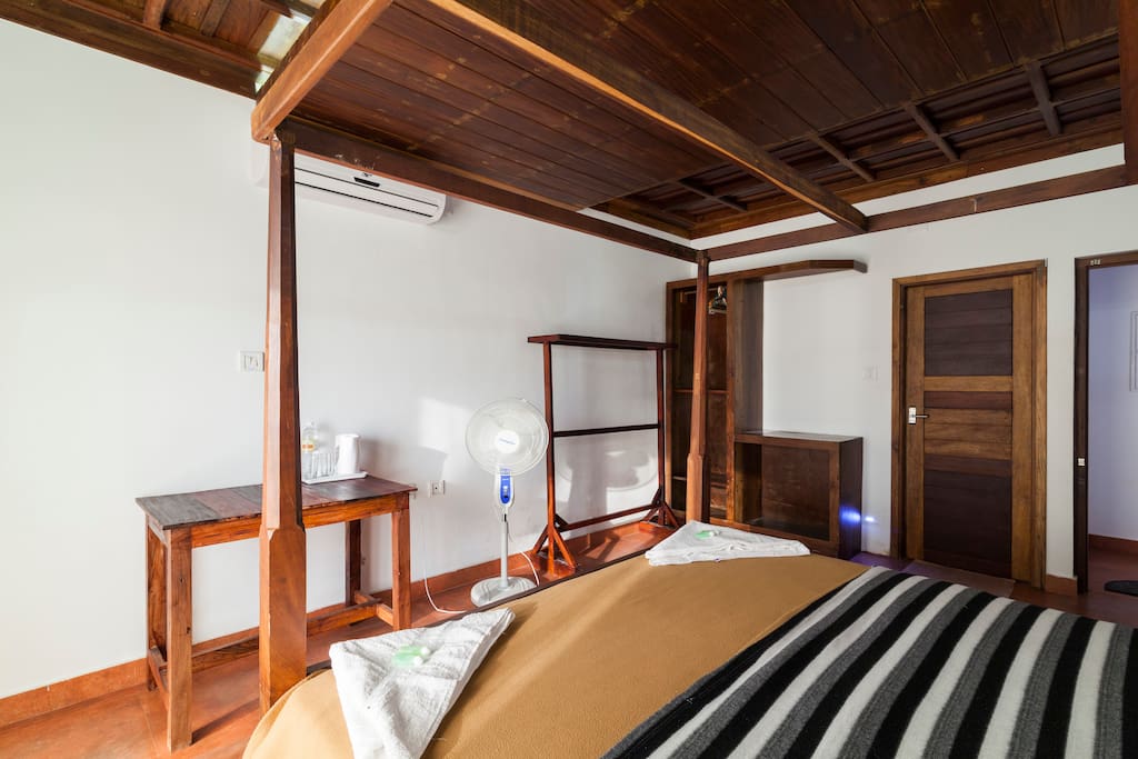 Room has table, chairs and a wooden stand to hang clothes