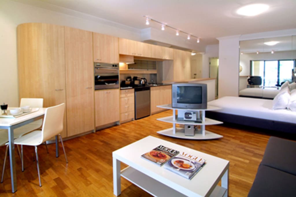 Living area with lounge sofa that converts to a double bed, 4 seater dining suite, LCD TV, and fully equipped kitchen