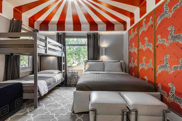 El dormitorio secundario cuenta con un techo de circo pintado y papel de pared de cebra Scalamandre.
Cuenta con una cama tamaño queen y literas individuales.  Esta habitación también cuenta con persianas opacas.
