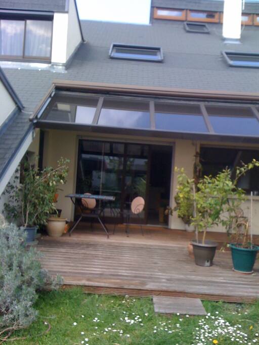 jolie verrière sur une terrasse en bois donnant sur le jardin
