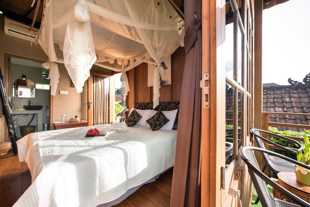 Lumbung suite with wooden floors and walls, enclosed ensuite bathroom and romantic draped net. Has air-con and fan cooling, Queen bed, quality cotton linens and views from the veranda.